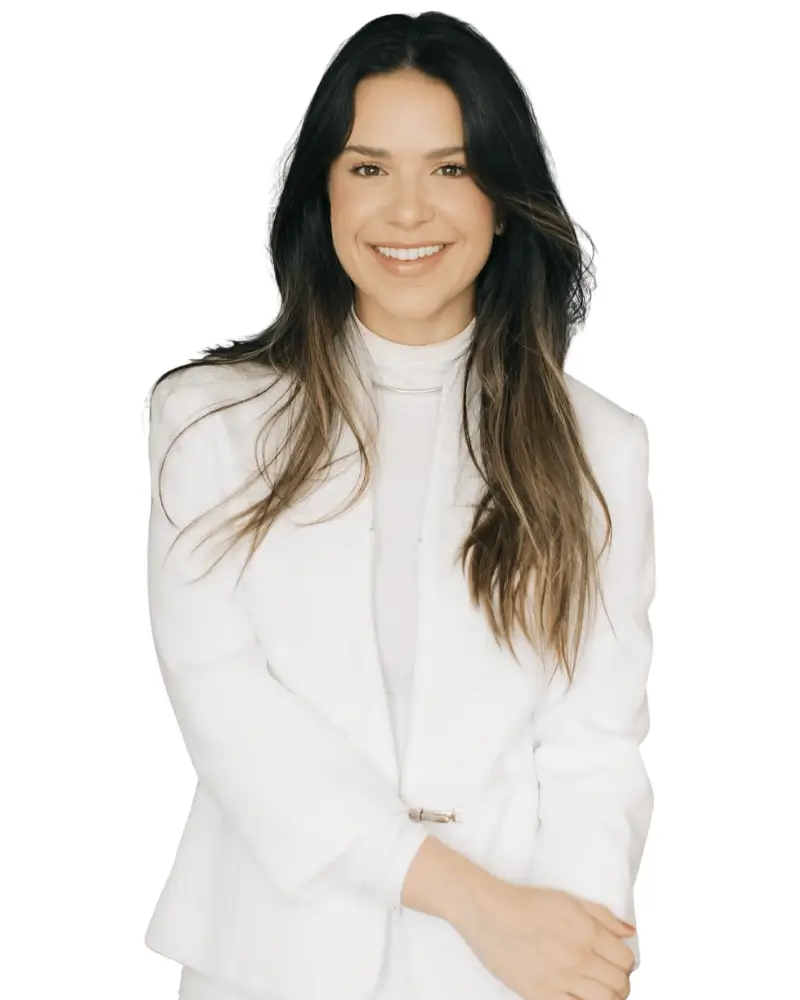 Fotografia de corpo inteiro da Dra. Amanda Caruso, médica focada em emagrecimento definitivo e reestruturação metabólica, sorrindo e posando com os braços cruzados contra um fundo branco isolado. Ela veste um blazer e calças brancas elegantes. A imagem transmite a confiança e a modernidade de seu atendimento médico humanizado.